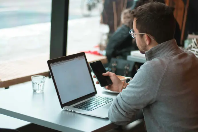 Person working remotely on laptop and phone, illustrating mobile connectivity