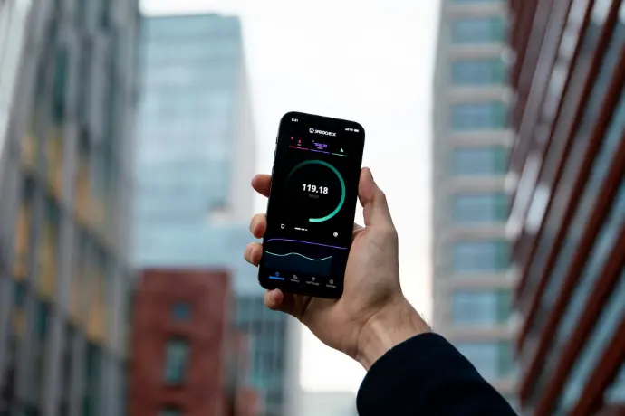 Hand holding smartphone showing internet speed test in cityscape, illustrating fast 5G mobile connectivity